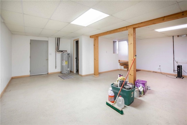 finished below grade area with water heater, a paneled ceiling, and baseboards