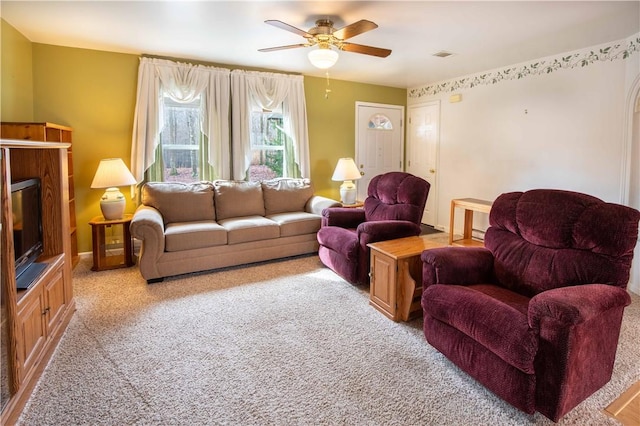 living room with light carpet, a glass covered fireplace, visible vents, and a ceiling fan