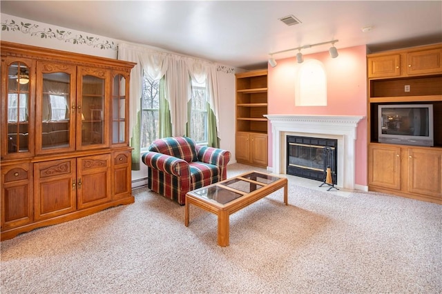 living room with a fireplace with flush hearth, carpet flooring, visible vents, and built in shelves