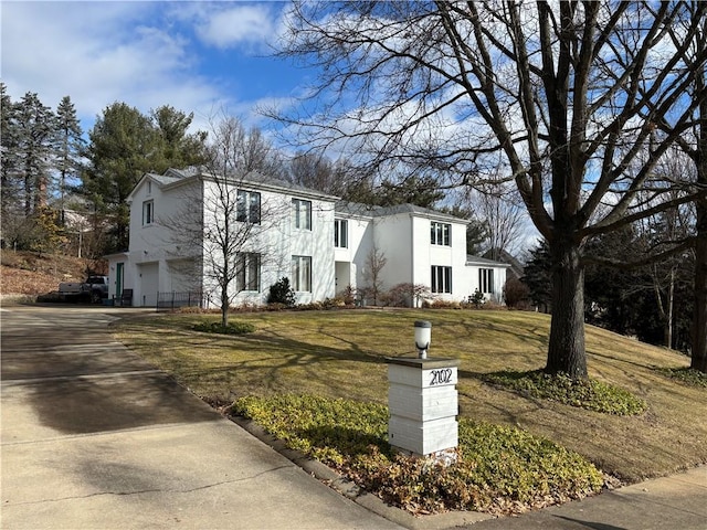 view of front of home with concrete driveway, a front lawn, an attached garage, and stucco siding