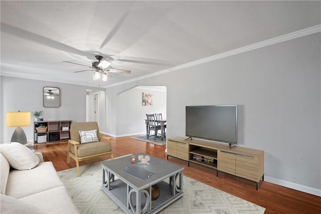 living area with arched walkways, ornamental molding, wood finished floors, and baseboards