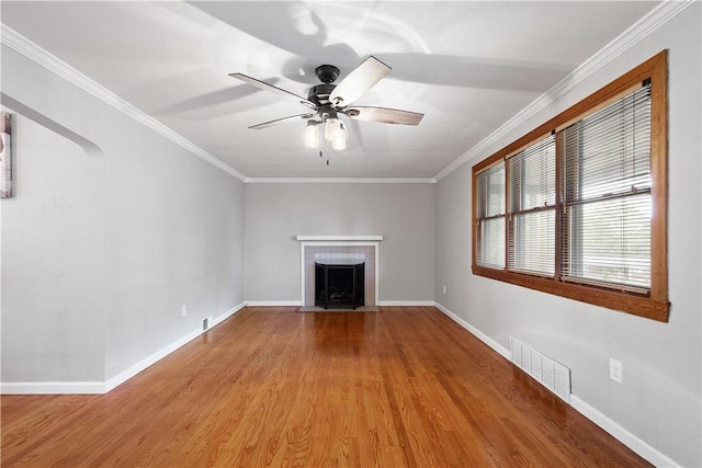 unfurnished living room featuring baseboards, a tiled fireplace, visible vents, and crown molding