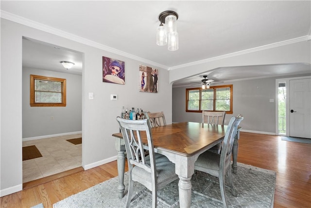 dining area featuring baseboards, light wood finished floors, arched walkways, and crown molding