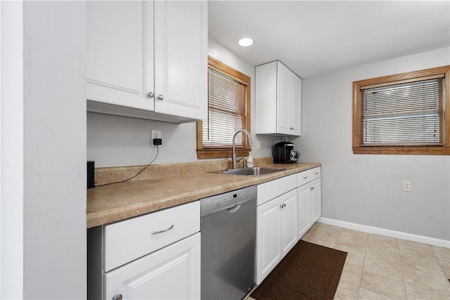 kitchen featuring baseboards, white cabinets, dishwasher, light countertops, and a sink