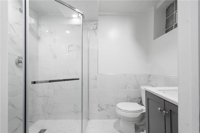 bathroom featuring toilet, a marble finish shower, tile walls, and vanity