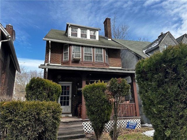 american foursquare style home featuring a chimney and brick siding