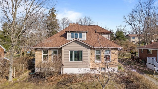 rear view of property featuring roof with shingles and a chimney