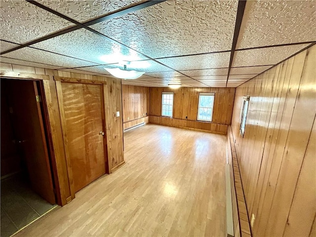 additional living space featuring a baseboard radiator, wood walls, and light wood-style flooring