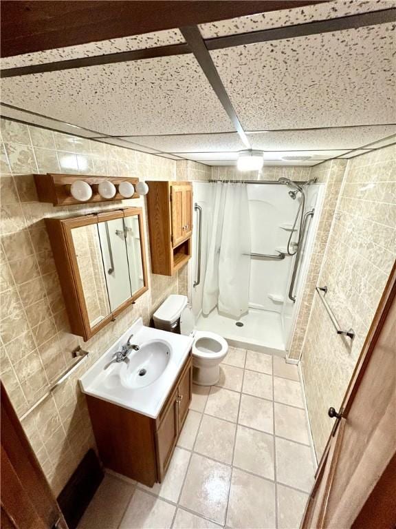 bathroom featuring toilet, tile patterned flooring, vanity, a shower stall, and tile walls