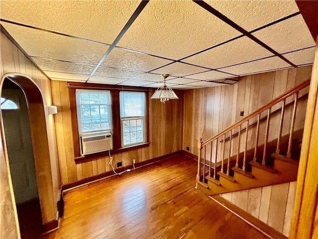 interior space featuring arched walkways, wood-type flooring, stairway, wood walls, and cooling unit