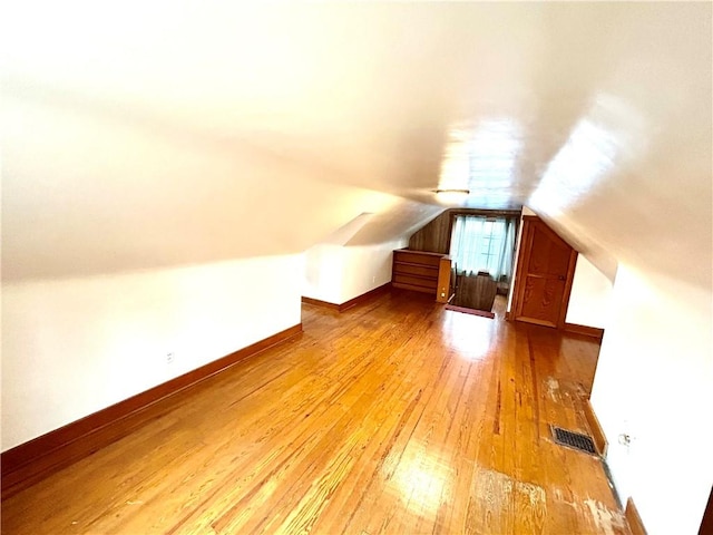 bonus room with light wood finished floors, baseboards, visible vents, and vaulted ceiling