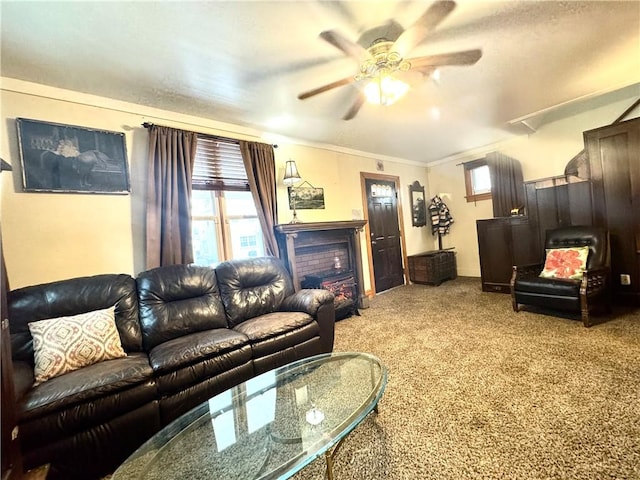 carpeted living area featuring a ceiling fan, crown molding, and a fireplace