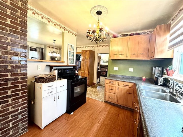 kitchen featuring pendant lighting, a notable chandelier, light wood finished floors, black electric range oven, and a sink