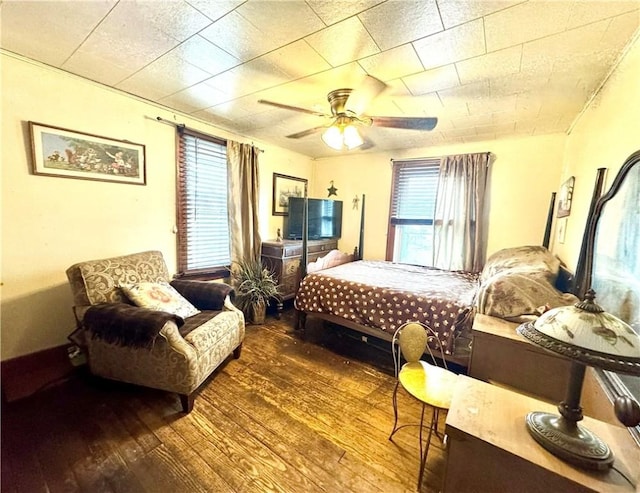 bedroom with multiple windows, a ceiling fan, and wood finished floors