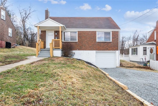 view of front of property with an attached garage, brick siding, a front lawn, a chimney, and gravel driveway