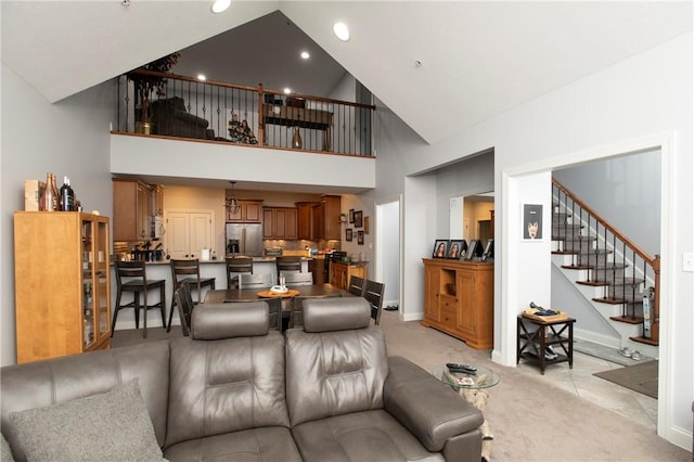 living area with high vaulted ceiling, recessed lighting, light carpet, baseboards, and stairs