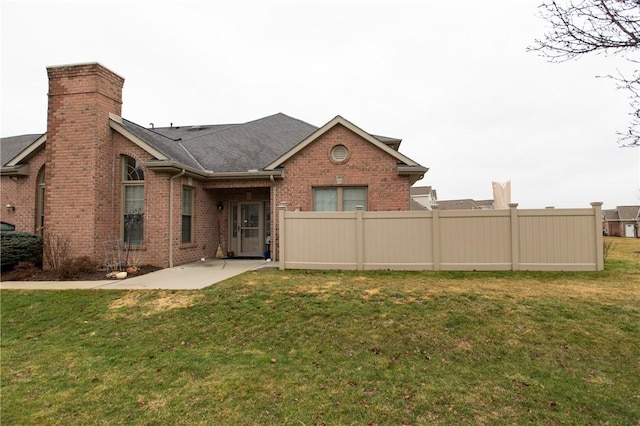 back of house featuring brick siding, a patio, a chimney, a lawn, and fence