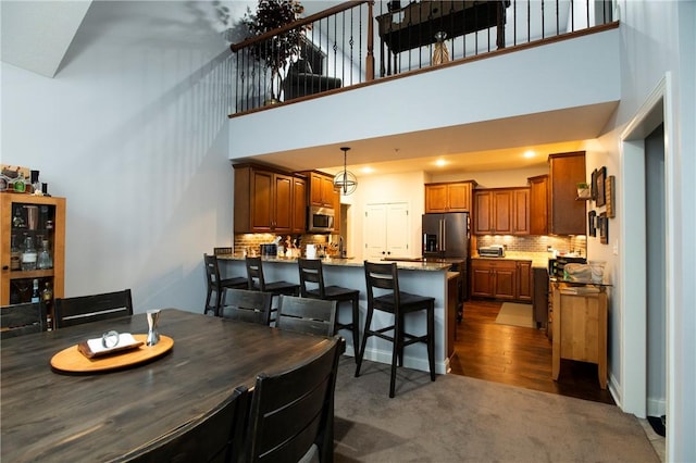 dining room featuring a high ceiling and dark colored carpet