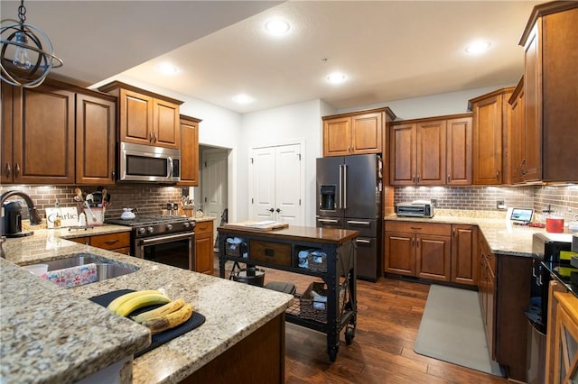 kitchen featuring dark wood-style floors, appliances with stainless steel finishes, light stone counters, and a sink