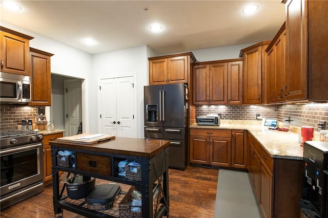 kitchen featuring dark wood finished floors, recessed lighting, decorative backsplash, appliances with stainless steel finishes, and light stone countertops