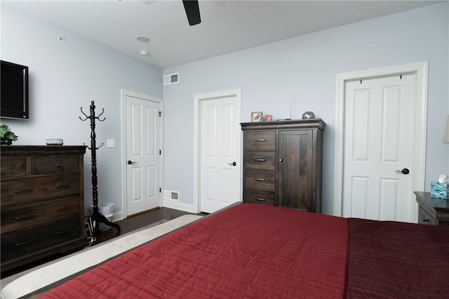 bedroom featuring a ceiling fan, visible vents, baseboards, and dark wood-style floors