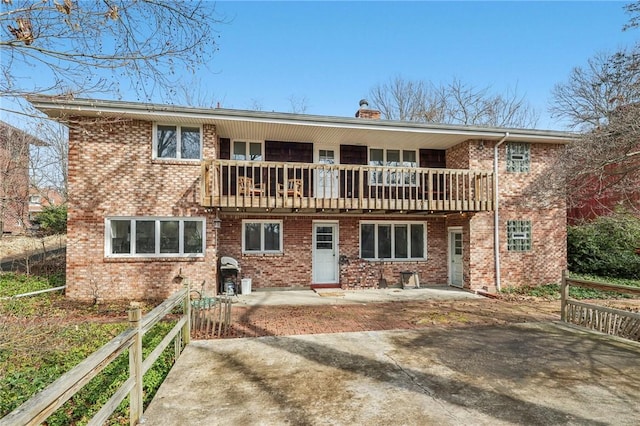 rear view of property featuring brick siding, a chimney, and a balcony