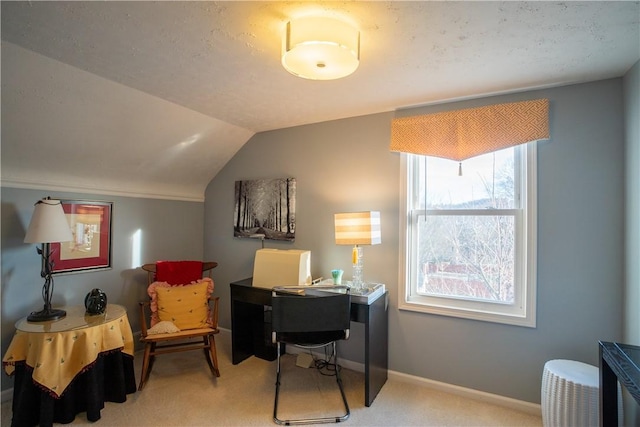 office area featuring light carpet, lofted ceiling, and baseboards