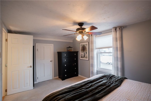 bedroom featuring baseboards, ornamental molding, a ceiling fan, and light colored carpet