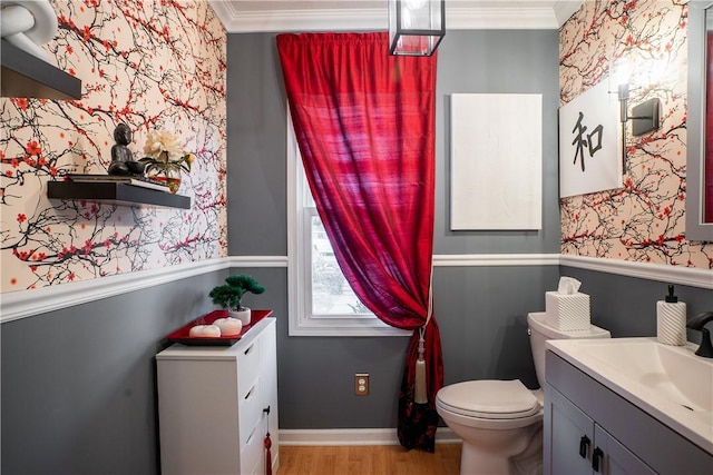 half bath with ornamental molding, wood finished floors, toilet, and wallpapered walls