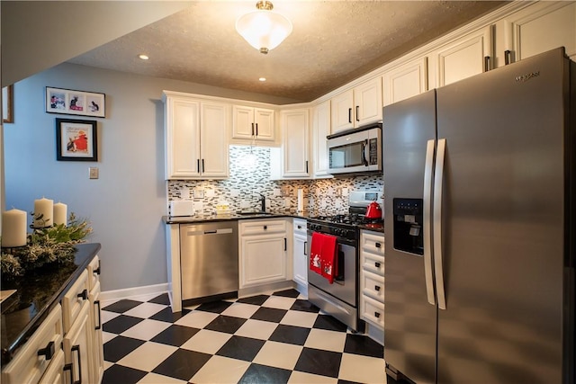 kitchen featuring stainless steel appliances, dark floors, backsplash, and dark countertops