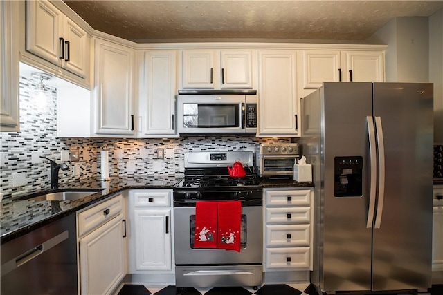 kitchen with stainless steel appliances, tasteful backsplash, dark stone countertops, and a sink