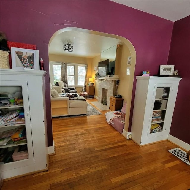 interior space featuring arched walkways, wood finished floors, visible vents, and baseboards