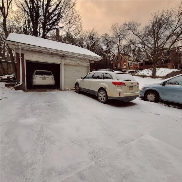 snow covered parking area featuring a garage