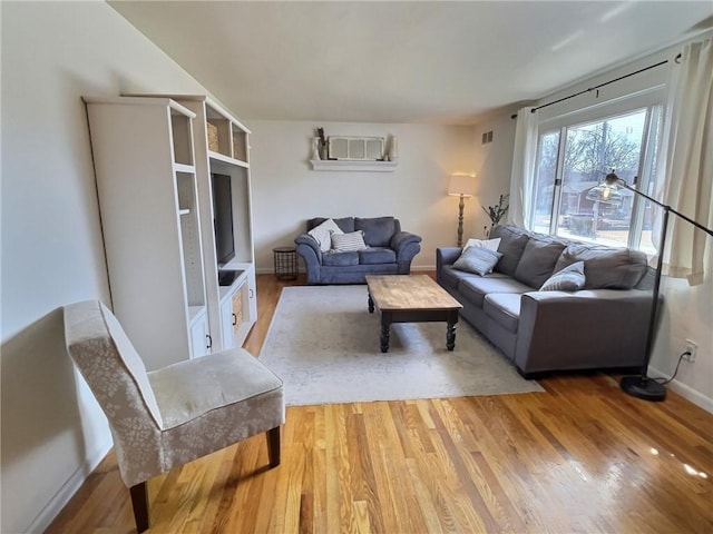 living room with baseboards, visible vents, and light wood finished floors