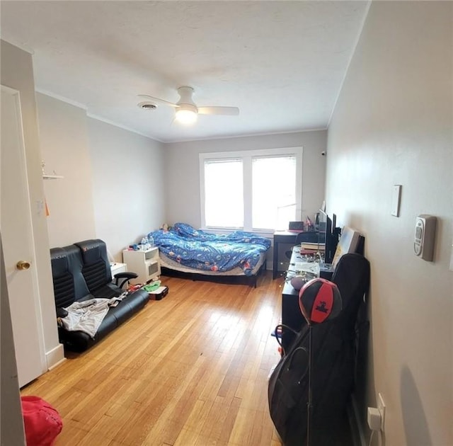 bedroom with light wood-type flooring, visible vents, ornamental molding, and a ceiling fan