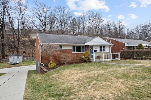 view of front facade featuring brick siding, a front yard, and a shingled roof