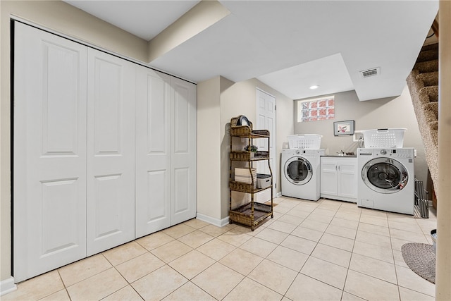 laundry room featuring light tile patterned flooring, visible vents, baseboards, cabinet space, and washer and clothes dryer