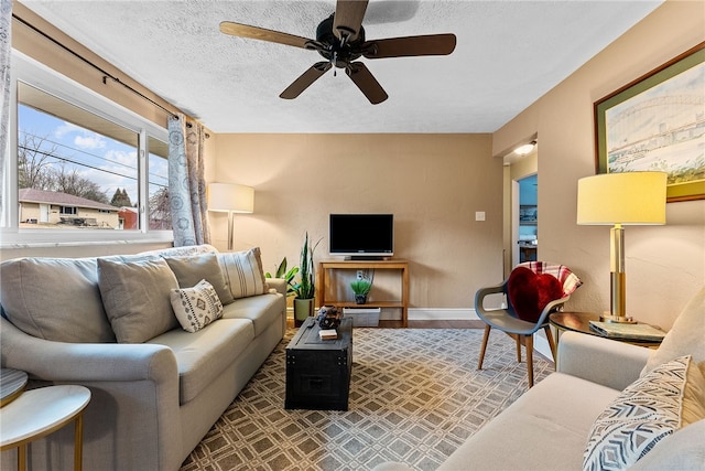 living room featuring ceiling fan, a textured ceiling, baseboards, and wood finished floors