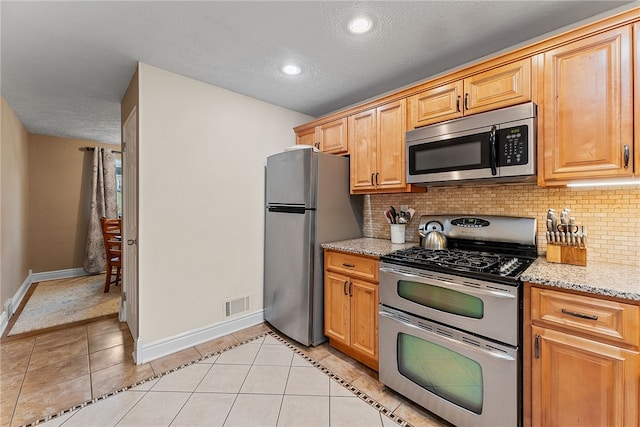 kitchen featuring light tile patterned floors, tasteful backsplash, visible vents, baseboards, and appliances with stainless steel finishes