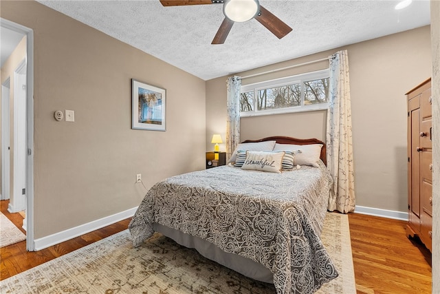 bedroom with a textured ceiling, wood finished floors, a ceiling fan, and baseboards