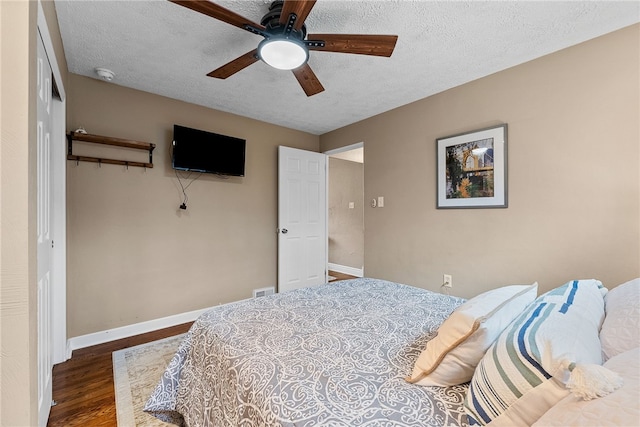 bedroom with a textured ceiling, ceiling fan, wood finished floors, baseboards, and a closet