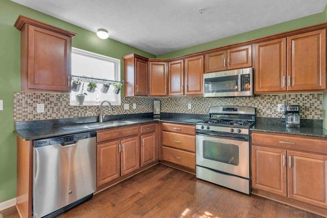 kitchen featuring appliances with stainless steel finishes, dark wood-type flooring, a sink, and tasteful backsplash