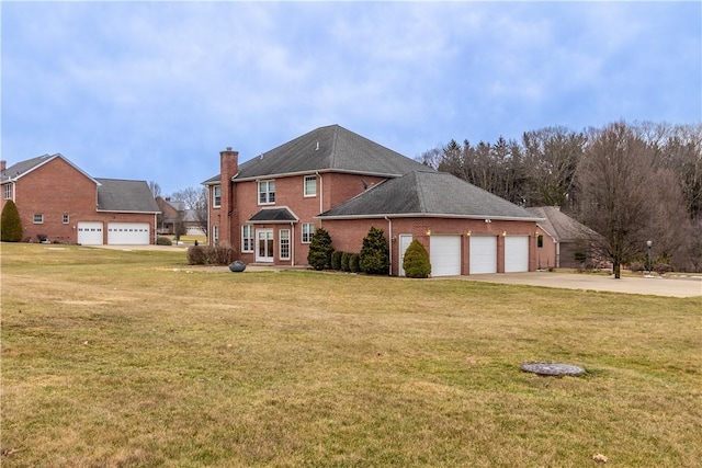 rear view of property with a garage, brick siding, a yard, and concrete driveway