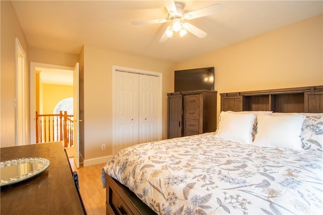 bedroom featuring lofted ceiling, a closet, light wood-style floors, ceiling fan, and baseboards