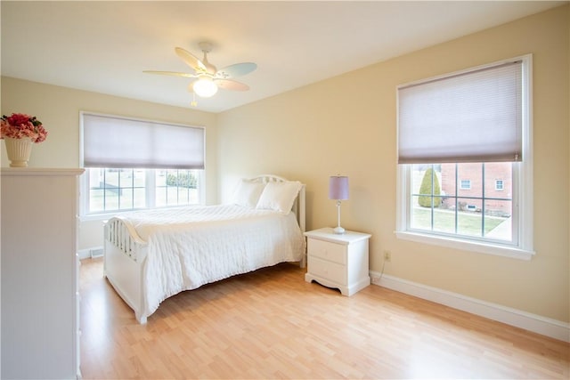 bedroom featuring light wood-type flooring, multiple windows, and baseboards