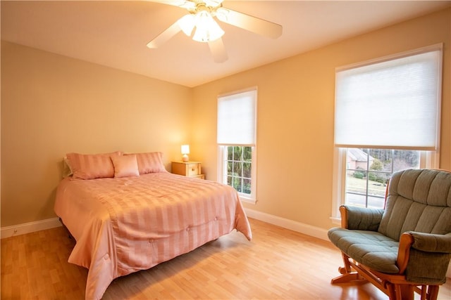 bedroom with multiple windows, light wood-style flooring, and baseboards