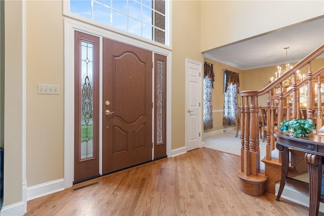 entrance foyer with wood finished floors, plenty of natural light, a notable chandelier, and stairs