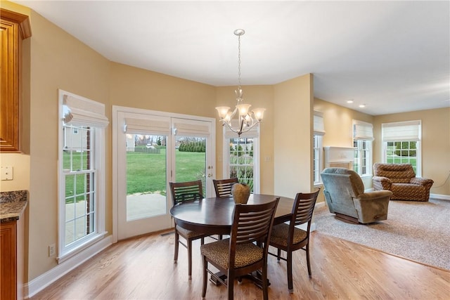 dining room featuring an inviting chandelier, baseboards, and light wood-type flooring