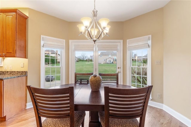 dining room with a healthy amount of sunlight, a notable chandelier, and light wood finished floors