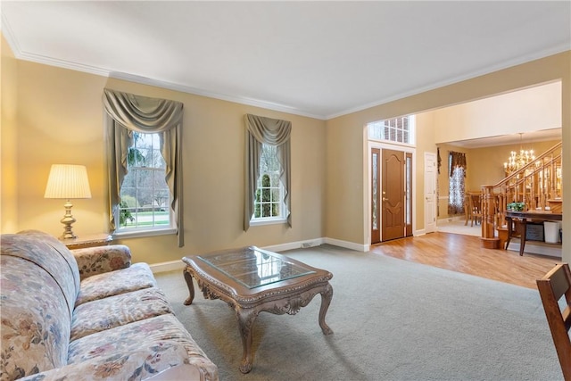 living area with crown molding, a notable chandelier, baseboards, and carpet floors